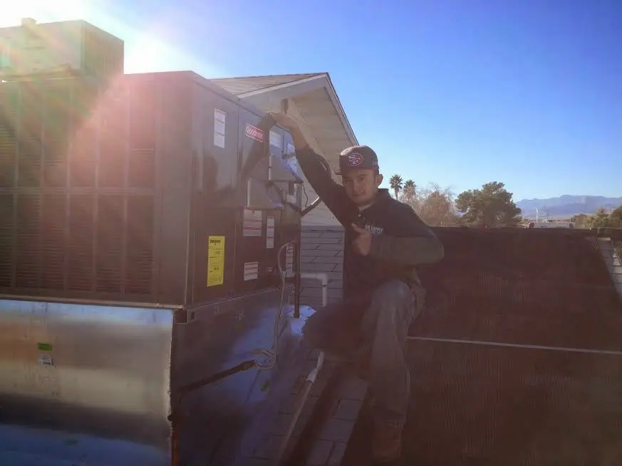 HVAC technician performing Heat Pump Repair on a rooftop unit in Warren